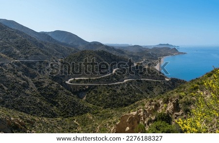 A winding road on the east coast of Spain Murcia mountains, blue sea and ship, Costa del Sol. A beautiful road along the sea with steep cliffs. View of the blue sky and the sea.