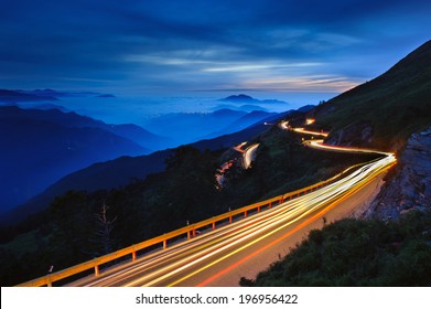 A Winding Road On A Mountain Being Lit Up At Night.