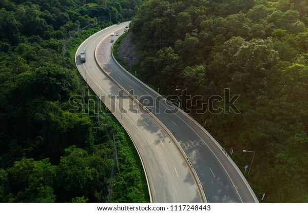 The winding road that cuts through\
the hilly terrain is a mountain that rises in the\
morning.