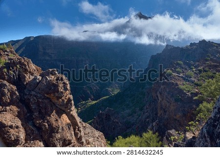 Winding road threading through the misty Masca gorge seen from a rocky ledge in the Teno massif