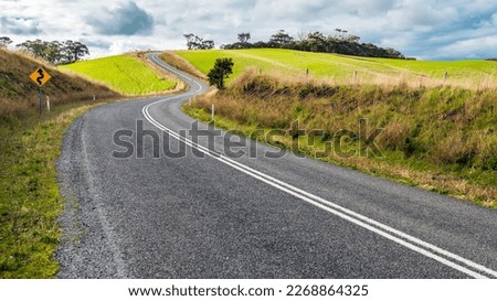 Winding road through Adelaide Hills farms during winter season, South Australia