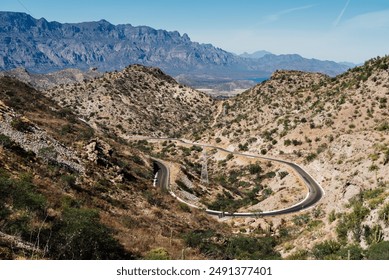 A winding road through the rugged mountains near the Sea of Cortez in Mexico. The dramatic landscape features rocky hills and distant mountain ranges, capturing the beauty of this arid region. - Powered by Shutterstock