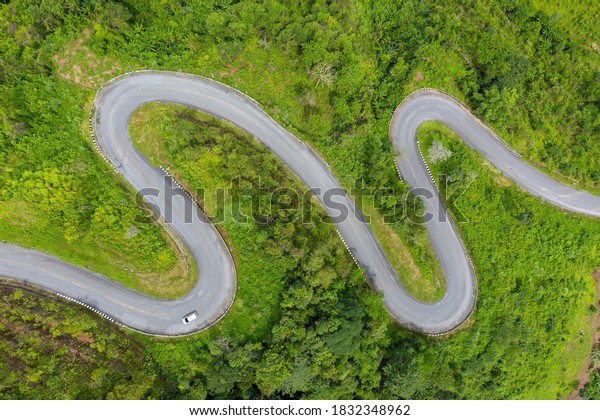Winding road, top view of the corner Look at the\
beautiful aerial view of asphalt roads, highways through mountains\
and forests in rainy season. For traveling and driving in nature.\
Nan thailand
