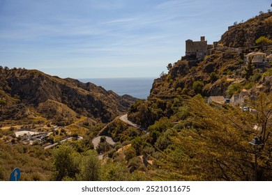 Winding roads weave through the rugged coastal landscape towards a village, framed by a brilliant blue sky and endless ocean view, presenting a perfect getaway destination. - Powered by Shutterstock