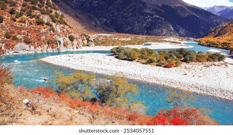 Winding turquoise river flows through vibrant autumn foliage, rocky banks, and lush greenery, set against dramatic mountainous scenery under a clear sky. - Powered by Shutterstock