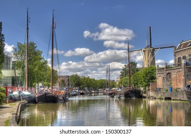 Windmill And Historical Boats In A Canal In Gouda, Holland