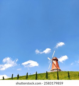 windmill up on a hill with a sky blue background 