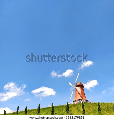 windmill up on a hill with a sky blue background 