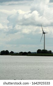Windmill on the river. Cloudy day photo.