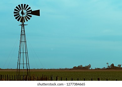Windmill over a green field and blue sky behind