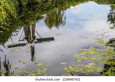 Windmill Reflection In A Small Town Park.