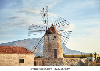 Windmill in the Saline di Trapani e Paceco natural reserve near Trapani, Sicily, Italy. Old windmill overlooking town of Erice on mountain - Shutterstock ID 2227267659