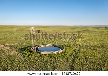 windmill with a water pump and tank  in shortgrass prairie, Pawnee National Grassland in Colorado, aerial view