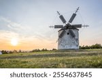 Windmill with wooden wings in a landscape setting. Fields, meadows and flowers appear in the sunset. Landscape shot in nature with a mill. historically untypical for the Balaton region, Hungary