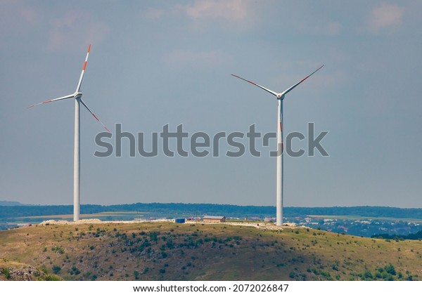 Windmills for electricity generation. Green energy\
concept. Background with copy space for text. Modern farm outside\
the city.