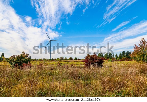 Windmills for electricity generation. Green energy\
concept. Background with copy space for text. Modern farm outside\
the city.