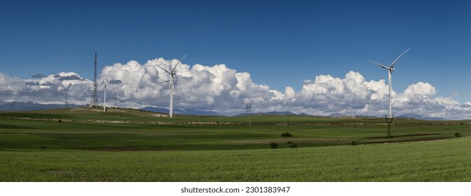 Windmills in the mountains. Mountain range with green grass, white fluffy clouds on the blue sky. - Powered by Shutterstock