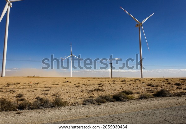 windmills on the\
road in the Jordan desert. symbolic image for the energy transition\
and climate change. copyspace. alternative energies are the future.\
wind energy in the\
desert.