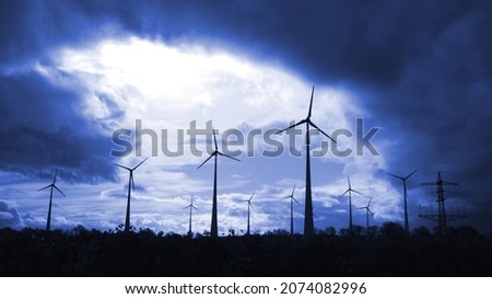 windmills producing electricity silhouetted in a dark blue sky