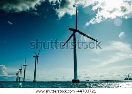 Windmills in a row against sun