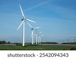 windmills in a row and electricity poles also in flat landscape in denmark