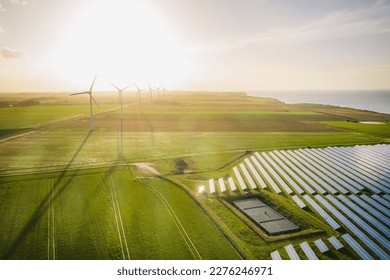 Windmills and solar panels farm in green fields close to the ocean. Renewable energies concept. Green energy for carbon dioxide emission reduction.  - Powered by Shutterstock