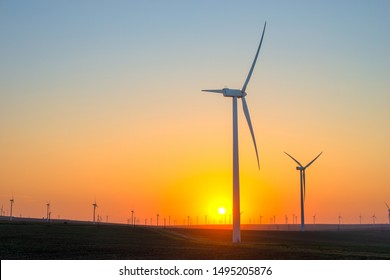 Windmills And Sunset Over Field