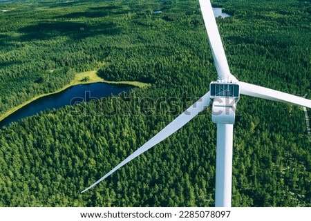Windmills, wind turbines. Aerial view of windmills in green summer forest in Finland. Wind turbines for electric power with clean and Renewable Energy