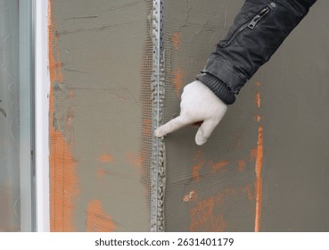 Window angle bead.  Close up on applying a coat of plaster, finish over the house window angle bead, reinforcing mesh outdoors. Angle Beading.