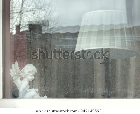 the window to the apartment is decorated with a figurine of an angel and a floor lamp close-up