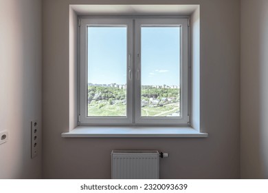 La ventana del apartamento da al bosque verde y al cielo azul.