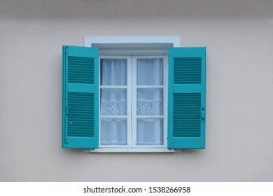 Window with blue wooden, open shutters and curtains on white wall background. Facade of traditional building, close up. - Powered by Shutterstock