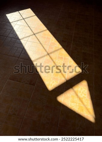 A window casts a shadow on the floor, creating a triangular shape. The light is coming from the right side of the image