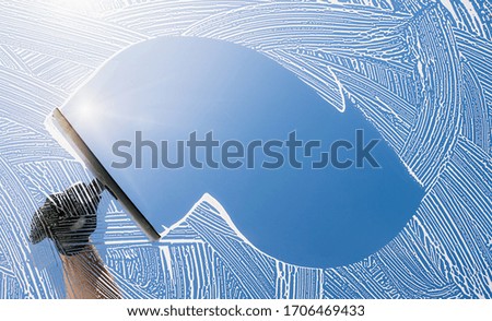window cleaner cleaning window with squeegee and wiper on a sunny day
