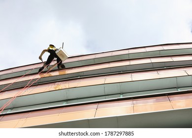 Window Cleaner Hangs On Rope And Washes Windows. Industrial Mountaineer Services Concept