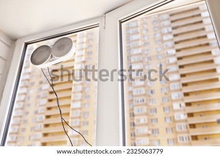 a window cleaner robot cleans dirt on a window pane against the background of a multi-storey building and the sky.