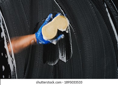 window cleaner with sponge cleaning glass window on dark background