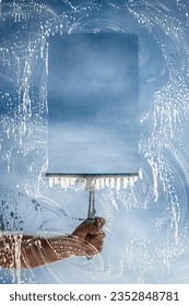 Window cleaner using a squeegee to wash a window with clear blue sky background