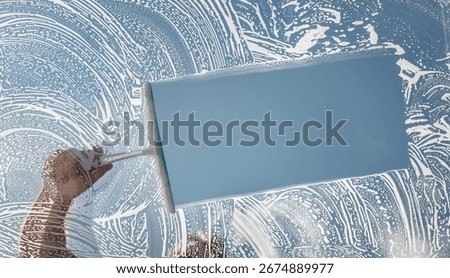 Window cleaner using a squeegee to wash and clean a window with clear blue sky