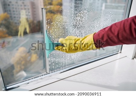 Window cleaner washing windowpane using implement with rubber blade