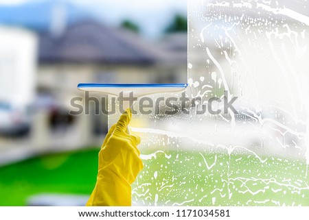 Window cleaner for washing a windows. Hand in yellow glove hold cleaning squeegee. 