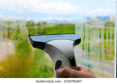 Window cleaning with glass cleaner. Man's hand holding a windshield wiper.Hand washes the window with a windshield wiper