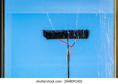 Window Cleaning Using Telescopic Water Brush And Wash System. Commercial Window Cleaning From The Outside With Sky In Background. Defocused