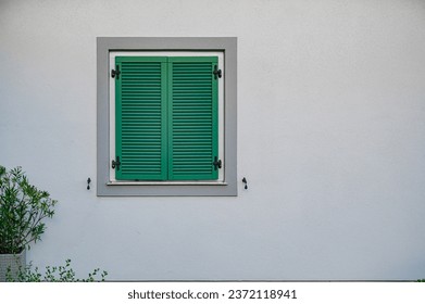 The window is closed with green shutters. Calm background with free space. - Powered by Shutterstock