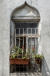 A Window With Distinct, Onion-dome Design, Metal Bars And A Flower Box With Red Geraniums On A Building In Tbilisi, Republic Of Georgia. 