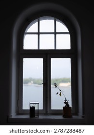 The window is divided into two sections: a traditional double-pane lower window with a central latch, and a semi-circular arched transom window on top divided into six smaller glass panes.