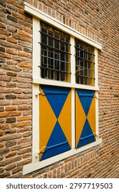 Window features diamond-patterned shutters and a brick facade, showcasing historical architectural elements.