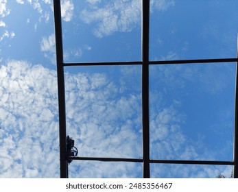 Window frame and blue sky with clouds. Outside the office window.