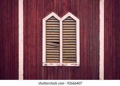 Window frame with shutters on rustic red wooden wall