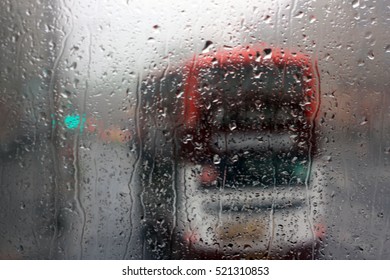 Window Glass With Rain Drops And British Bus Outside In Great Britain.